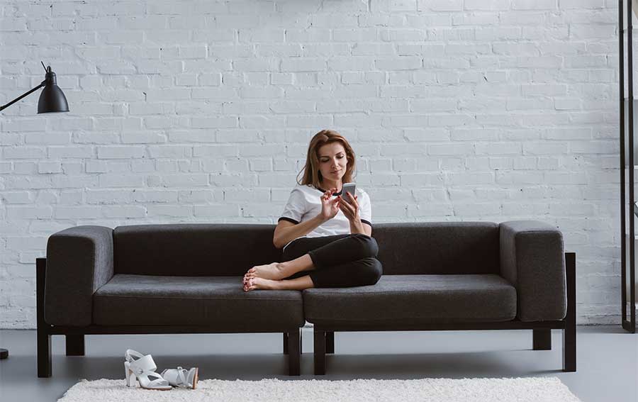 woman sitting on couch looking at her cell phone