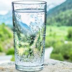 Clear, Healthy Drinking Water in a glass with view of mountains in the background